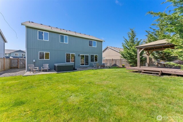 rear view of house featuring a gazebo, a fenced backyard, a hot tub, and a deck