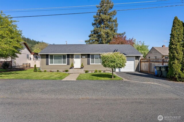 ranch-style home featuring fence, a shingled roof, an attached garage, a front yard, and driveway
