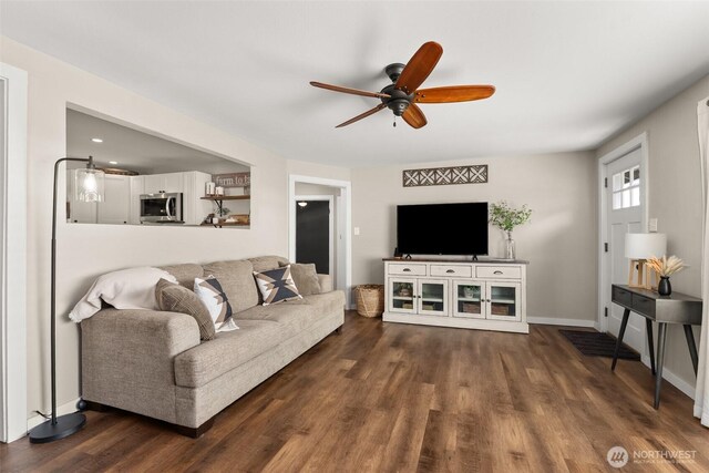 living room featuring baseboards, ceiling fan, and dark wood-style floors