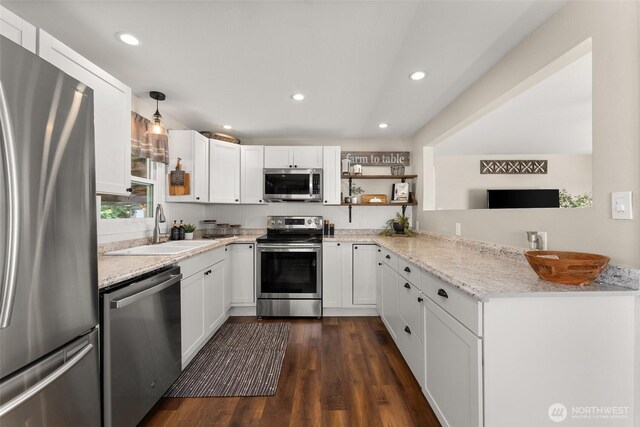 kitchen featuring open shelves, appliances with stainless steel finishes, a sink, dark wood finished floors, and a peninsula