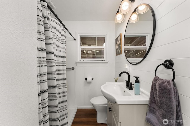 bathroom with vanity, toilet, a shower with shower curtain, baseboards, and wood finished floors