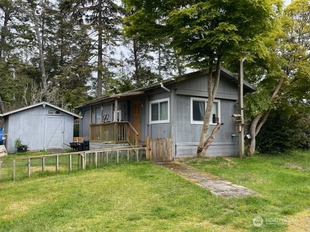 rear view of house with a storage shed, fence, an outbuilding, and a yard