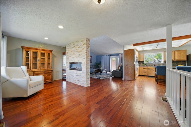 living room with recessed lighting, a textured ceiling, a fireplace, and hardwood / wood-style floors