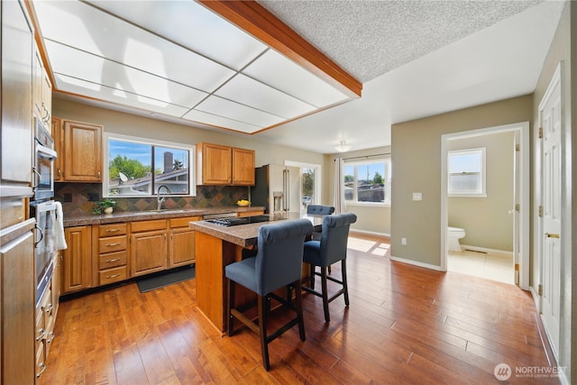 kitchen featuring a breakfast bar, a sink, a center island, stainless steel appliances, and tasteful backsplash
