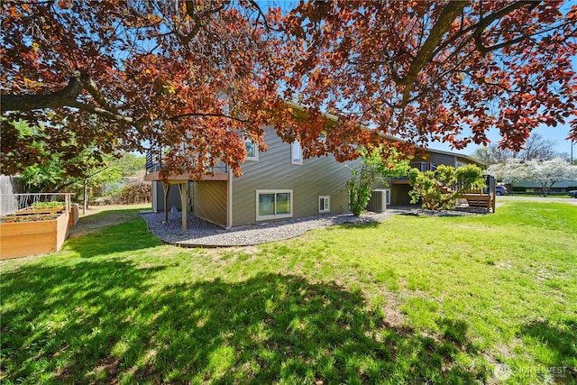 back of house with a lawn, central air condition unit, and a vegetable garden