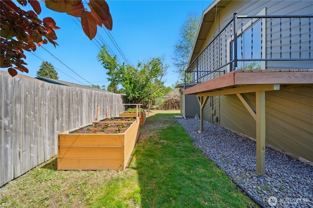 view of yard featuring fence, a garden, and a deck