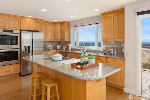 5310 143rd Ave SE, Bellevue, WA 98006 - kitchen with appliances with stainless steel finishes, a kitchen breakfast bar, light wood-style flooring, a sink, and a kitchen island