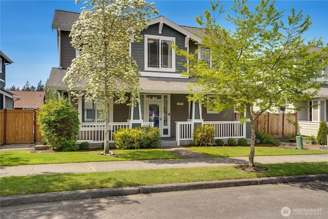 view of front of home with covered porch, fence, and a shingled roof