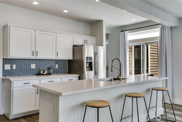 kitchen featuring stainless steel refrigerator with ice dispenser, dark wood-style floors, a sink, and white cabinetry