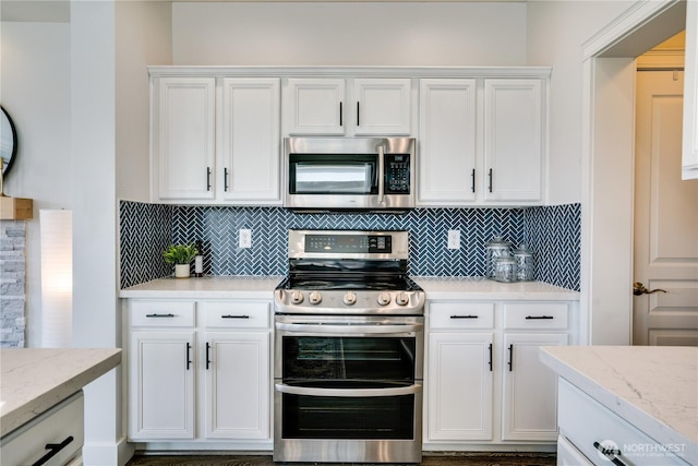 kitchen featuring decorative backsplash, white cabinetry, appliances with stainless steel finishes, and light stone countertops