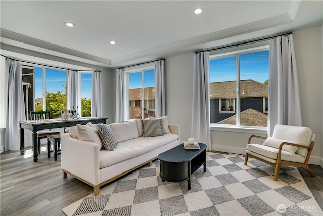 living area featuring crown molding, a raised ceiling, light wood-type flooring, and recessed lighting