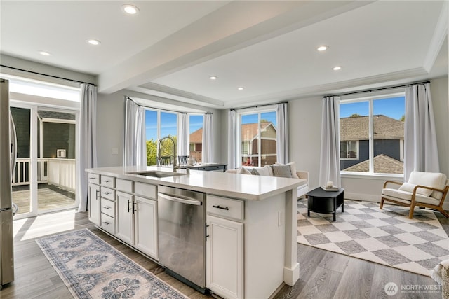 kitchen with white cabinets, a sink, light countertops, stainless steel appliances, and wood finished floors