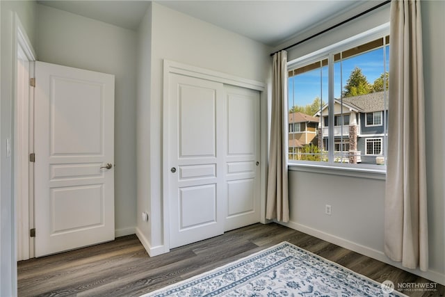 unfurnished bedroom featuring a closet, baseboards, and wood finished floors