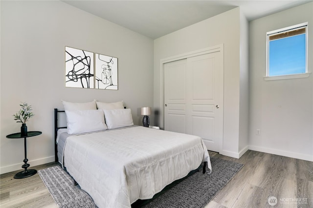 bedroom with baseboards, wood finished floors, and a closet