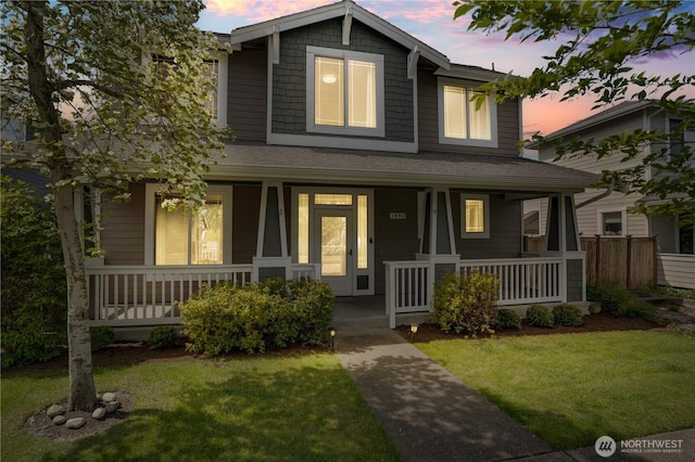 traditional-style house with covered porch, roof with shingles, and a front lawn