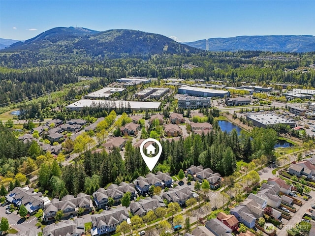 aerial view of residential area featuring mountains and a forest