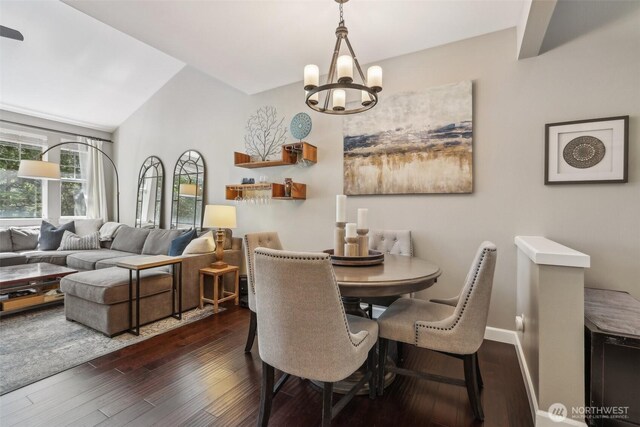 dining space with a chandelier, dark wood-style flooring, baseboards, and lofted ceiling