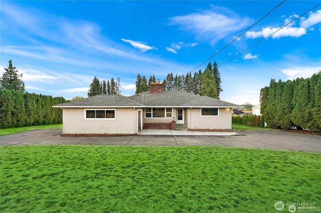 back of property with a lawn, a chimney, and stucco siding