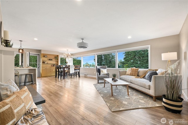 living area featuring recessed lighting, baseboards, a notable chandelier, and light wood-style floors