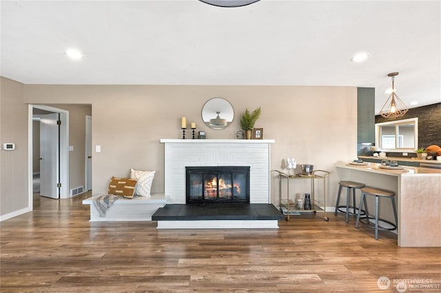 living area featuring baseboards, visible vents, wood finished floors, and a fireplace
