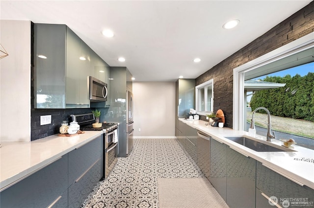 kitchen with stainless steel appliances, gray cabinets, a sink, and modern cabinets