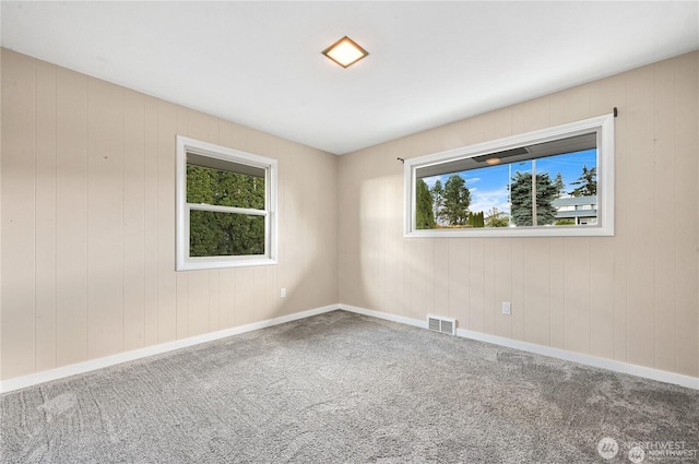 spare room featuring carpet floors, baseboards, and visible vents