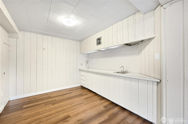 kitchen with light countertops, baseboards, a sink, and wood finished floors
