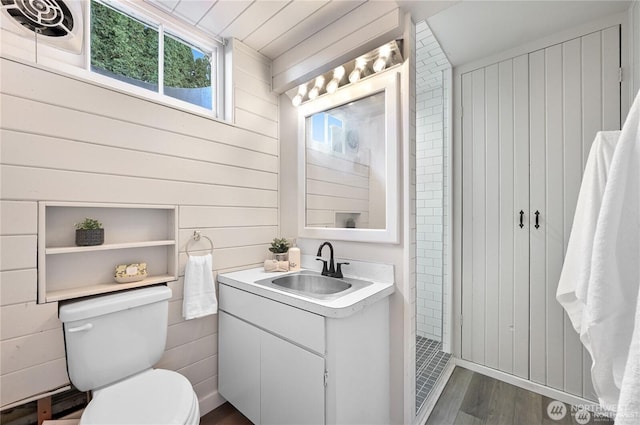 bathroom featuring vanity, wood finished floors, wooden walls, and toilet