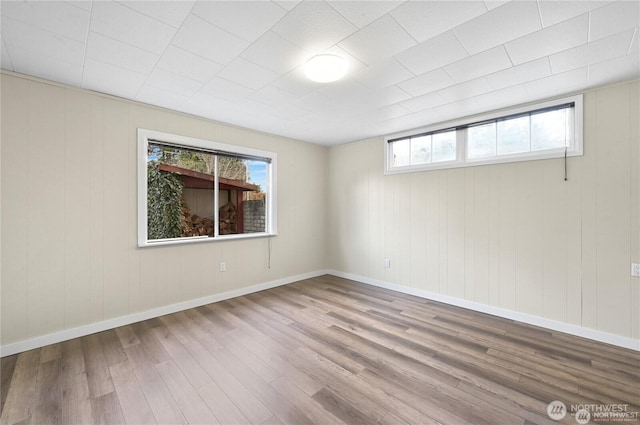 unfurnished room featuring baseboards, plenty of natural light, and wood finished floors