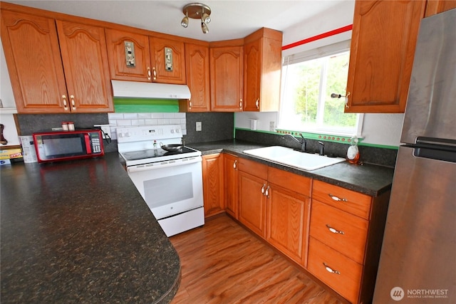 kitchen featuring brown cabinets, white range with electric stovetop, a sink, freestanding refrigerator, and under cabinet range hood