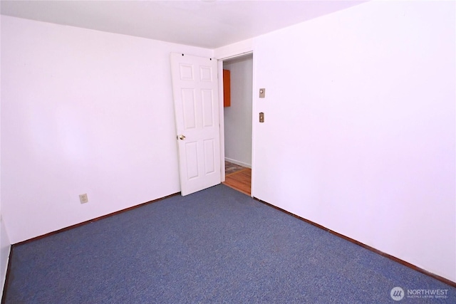 empty room featuring dark carpet and baseboards