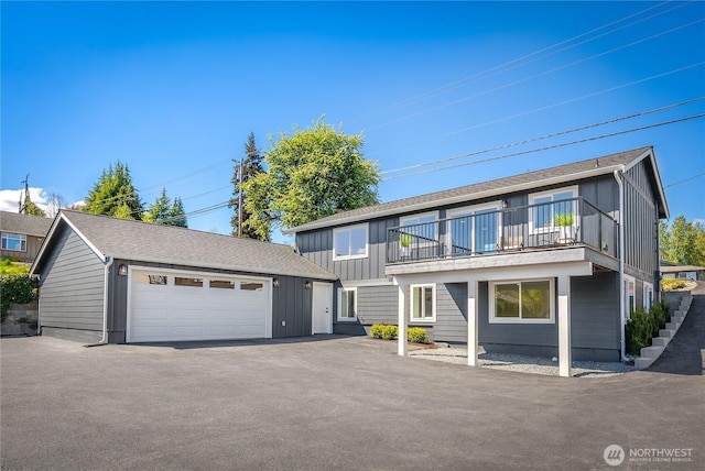 view of front of property featuring a detached garage, board and batten siding, an outbuilding, and a balcony