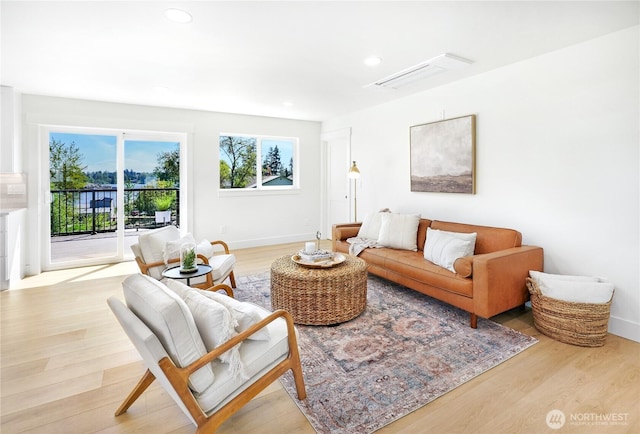 living room featuring light wood-style floors, baseboards, recessed lighting, and visible vents