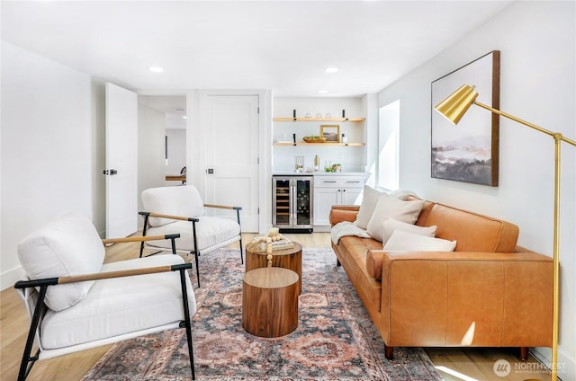 living area featuring beverage cooler, recessed lighting, a dry bar, and wood finished floors