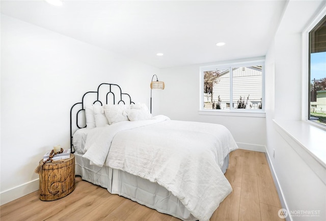 bedroom featuring baseboards, multiple windows, and wood finished floors