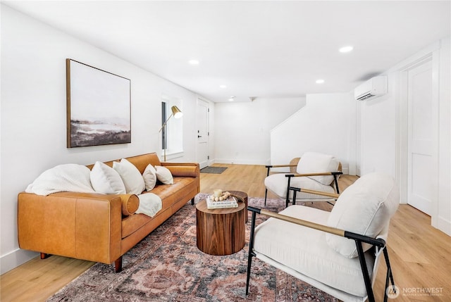 living room with light wood-type flooring, a wall mounted air conditioner, baseboards, and recessed lighting