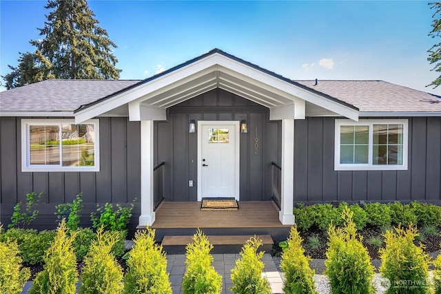 view of exterior entry with board and batten siding and roof with shingles