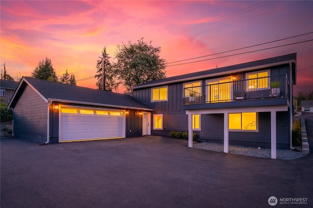 traditional home featuring board and batten siding, aphalt driveway, a balcony, and a garage