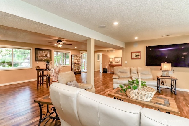 living area with recessed lighting, a textured ceiling, baseboards, and wood finished floors