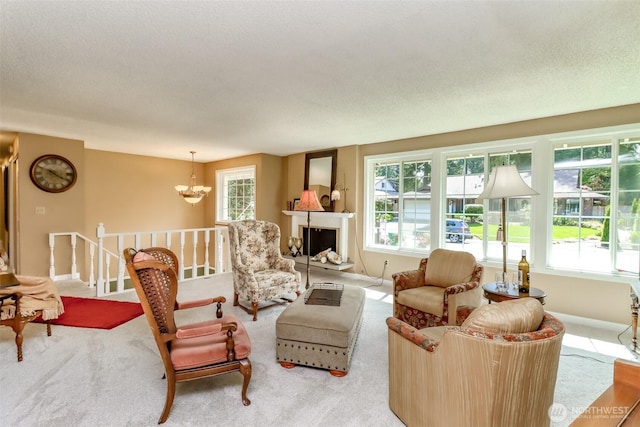 living area featuring an inviting chandelier, a fireplace with raised hearth, carpet, and baseboards