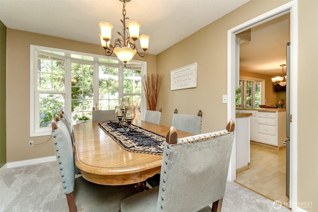 dining room with an inviting chandelier, baseboards, and light colored carpet