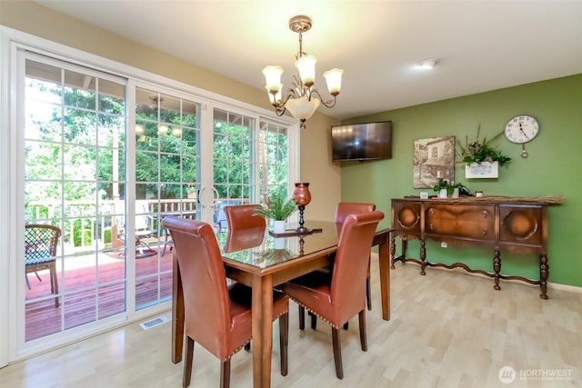 dining space featuring light wood-style floors, visible vents, and a notable chandelier