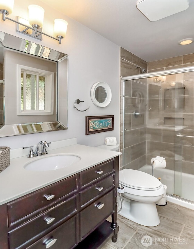 bathroom featuring vanity, a stall shower, and toilet