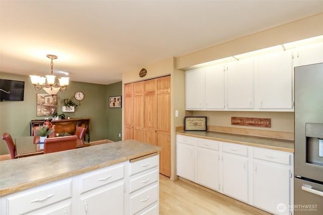 kitchen featuring an inviting chandelier, light countertops, stainless steel refrigerator with ice dispenser, and white cabinetry
