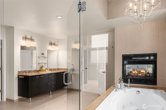325 6th Ave S, Kirkland, WA 98033 - full bathroom featuring double vanity, a multi sided fireplace, a tub with jets, tile patterned floors, and a notable chandelier