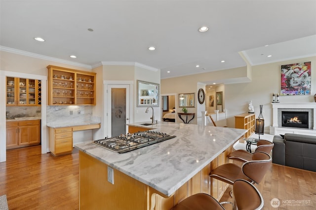 kitchen with backsplash, open shelves, stainless steel gas cooktop, light wood finished floors, and open floor plan