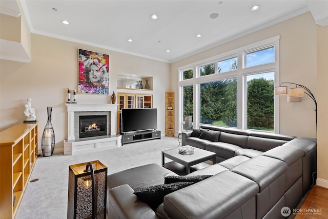 living area with crown molding, recessed lighting, baseboards, and a glass covered fireplace