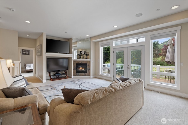 living area with light carpet, a fireplace, french doors, baseboards, and visible vents