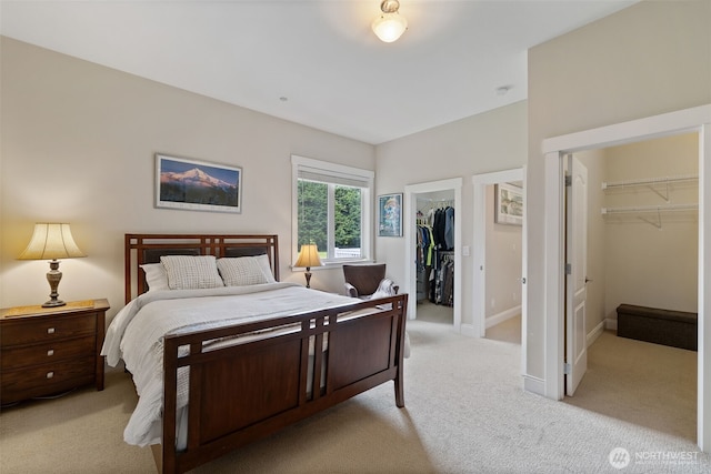 bedroom featuring light colored carpet, a walk in closet, and a closet