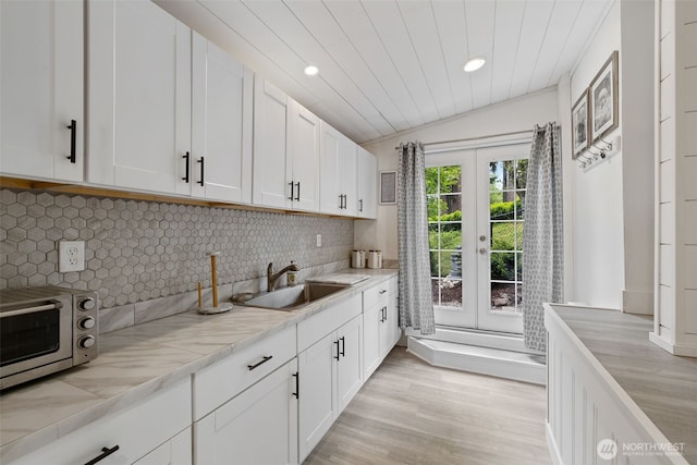 kitchen with a sink, light countertops, white cabinets, and french doors